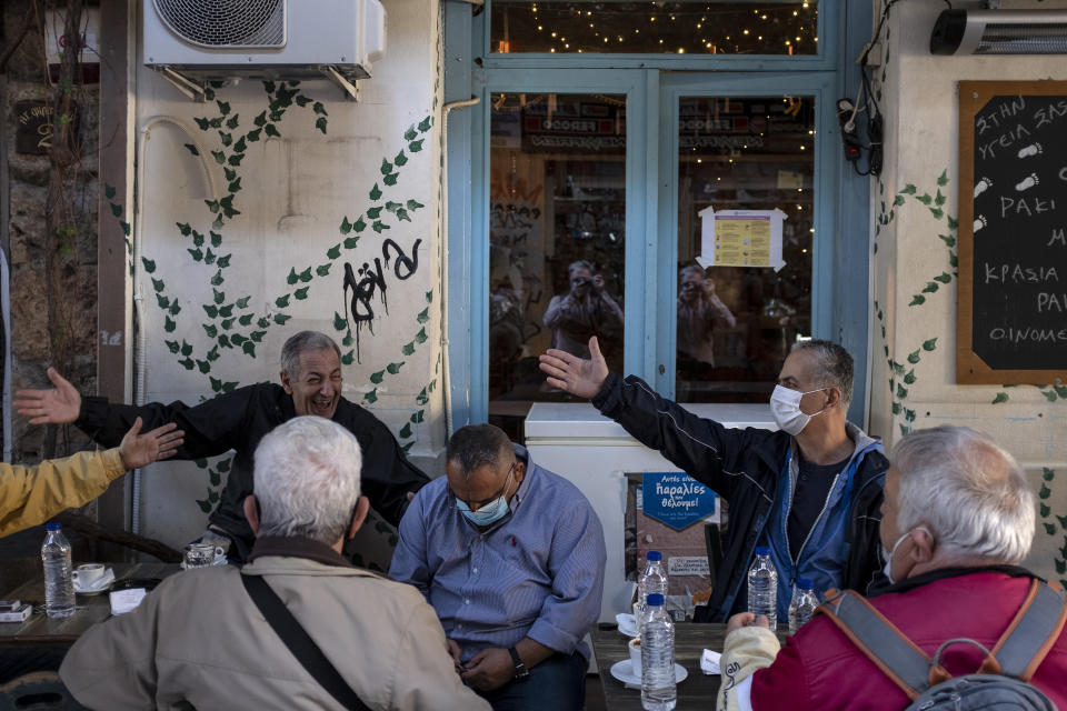 Locals chat as they sit at a traditional coffee shop in central Athens, Saturday, Oct. 31, 2020. Greece saw a jump in the number of confirmed coronavirus cases during last week, and Prime Minister Kyriakos Mitsotakis is widely expected to announce new social restrictions.(AP Photo/Yorgos Karahalis)