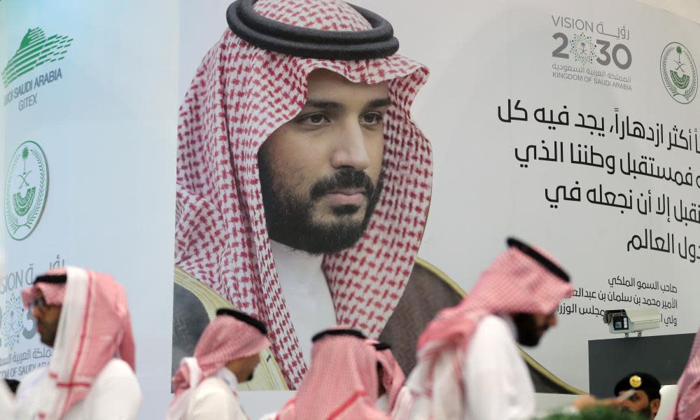 Saudis stand next to a portrait of Saudi Crown Prince Mohammed bin Salman at the Gitex 2018 exhibition at the Dubai World Trade Center in Dubai on Tuesday