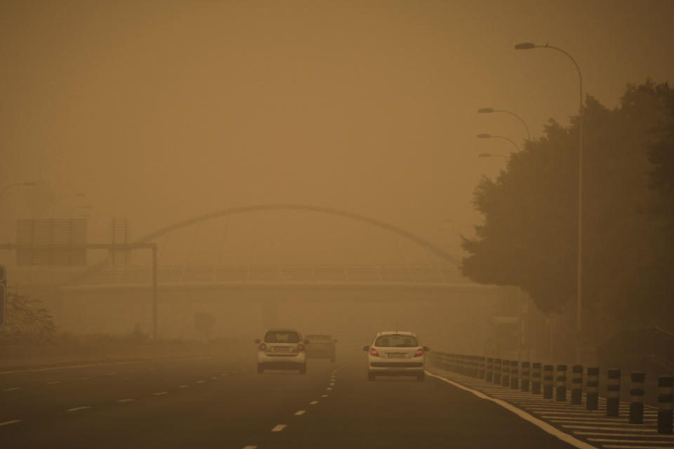 Cars drive in a cloud of red dust in Santa Cruz de Tenerife, Spain, Sunday, Feb. 23, 2020. Flights leaving Tenerife have been affected after storms of red sand from Africa's Saharan desert hit the Canary Islands. (AP Photo/Andres Gutierrez)