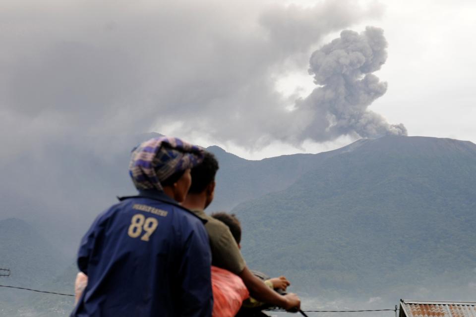 Motorists ride past by as Mount Marapi spews volcanic materials during its eruption in Agam, West Sumatra, Indonesia, Monday, Dec. 4, 2023. The volcano spewed thick columns of ash as high as 9,800 feet into the sky in a sudden eruption Sunday and hot ash clouds spread several miles.