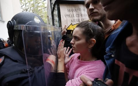 Spanish police push people with a shield outside a polling station in Barcelona - Credit: PAU BARRENA/AFP/Getty Images