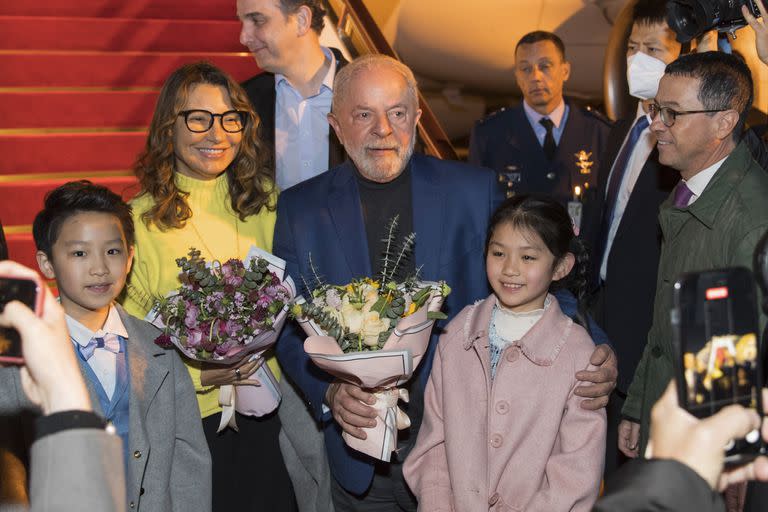 En esta foto publicada por la Agencia de Noticias Xinhua, el presidente brasileño Luiz Inacio Lula da Silva y la primera dama Rosangela Silva reciben flores presentadas por niños del Palacio de los Niños de Shanghai del Instituto de Bienestar de China a su llegada a Shanghai, China, el miércoles 12 de abril de 2023. 