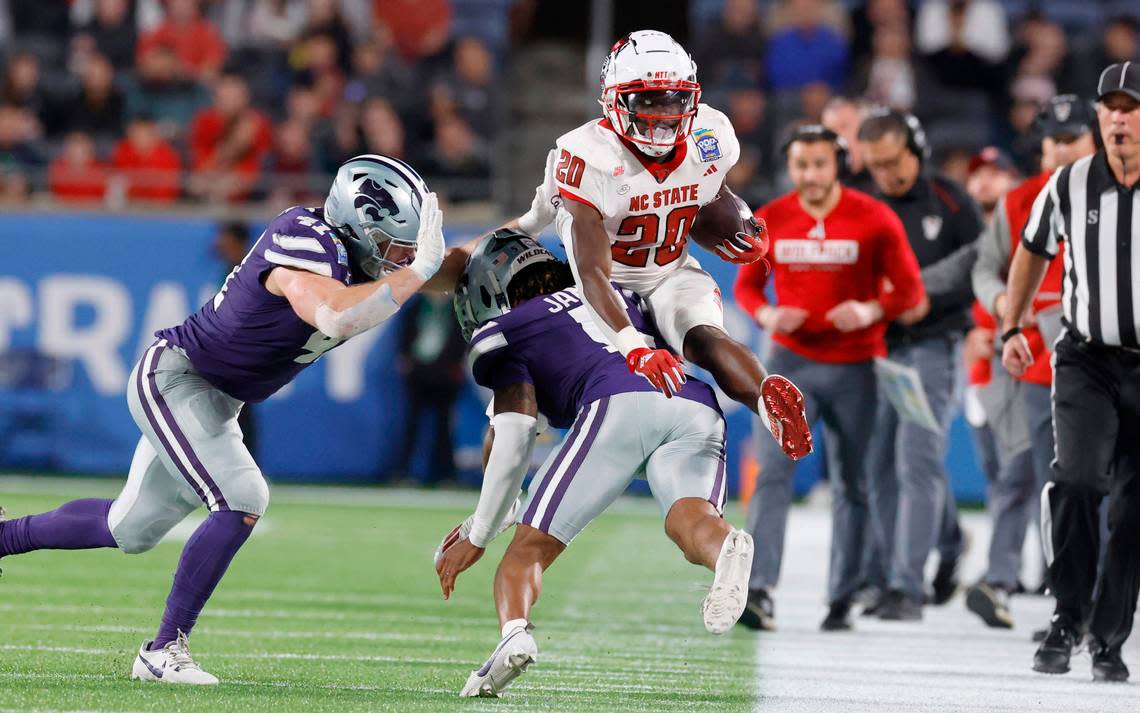 N.C. State running back Kendrick Raphael (20) hurdles over Kansas State cornerback Justice James (5) during the first half of N.C. State’s game against Kansas State in the Pop-Tarts Bowl at Camping World Stadium in Orlando, Fla., Thursday, Dec. 28, 2023. Ethan Hyman/ehyman@newsobserver.com