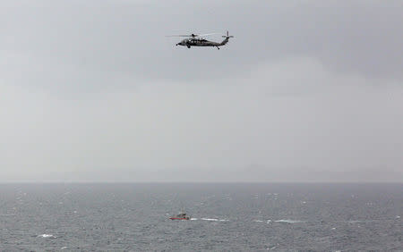 A Iranian Revolutionary Guard boat is seen near the U.S. aircraft carrier, USS George H. W. Bush while transiting Straits of Hormuz as U.S. Navy helicopter hovers over it during early hours of March 21, 2017. Picture taken March 21, 2017. REUTERS/Hamad I Mohammed