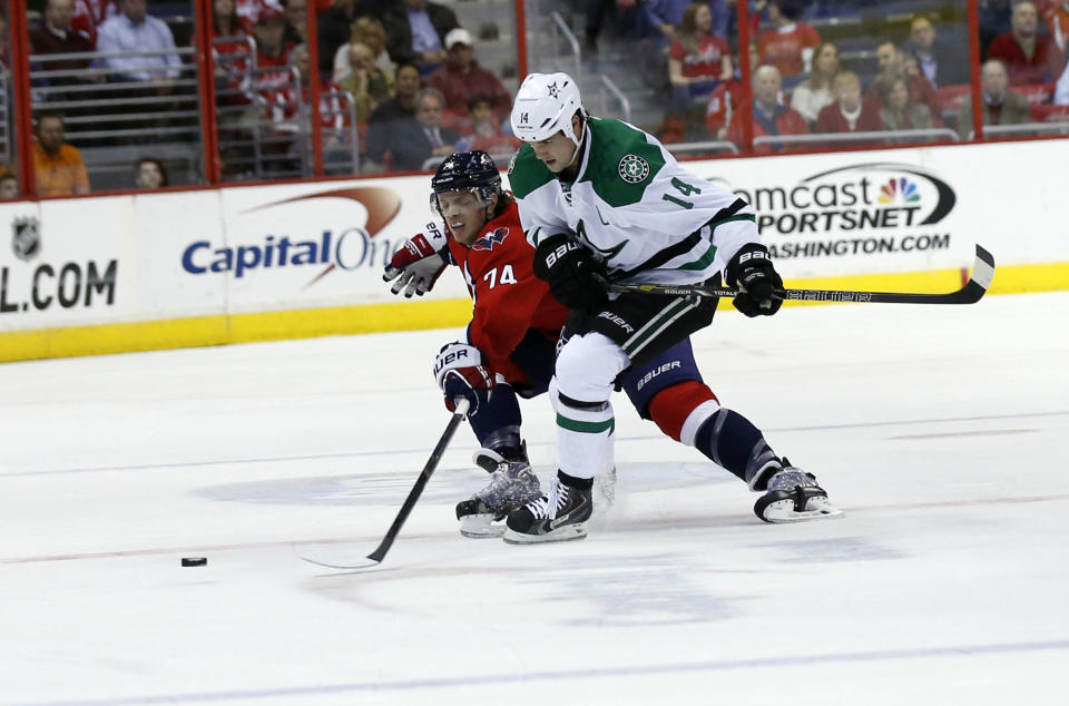 Washington Capitals defenseman John Carlson (74) reaches for the puck with Dallas Stars left wing Jamie Benn (14) in the first period of an NHL hockey game, Tuesday, April 1, 2014, in Washington. (AP Photo/Alex Brandon)