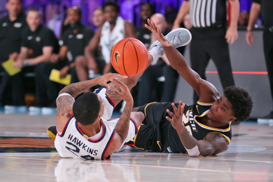 In this photo provided by Bahamas Visual Services, Connecticut guard Jordan Hawkins (24) and VCU forward Hason Ward (20) battle for a loose ball during an NCAA college basketball game at Paradise Island, Bahamas, Friday, Nov. 26, 2021. (Craig Lenihan/Bahamas Visual Services via AP)