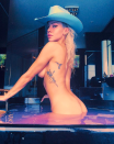 <p>The model is seen posing in a bathtub wearing nothing but a cowboy hat.</p>