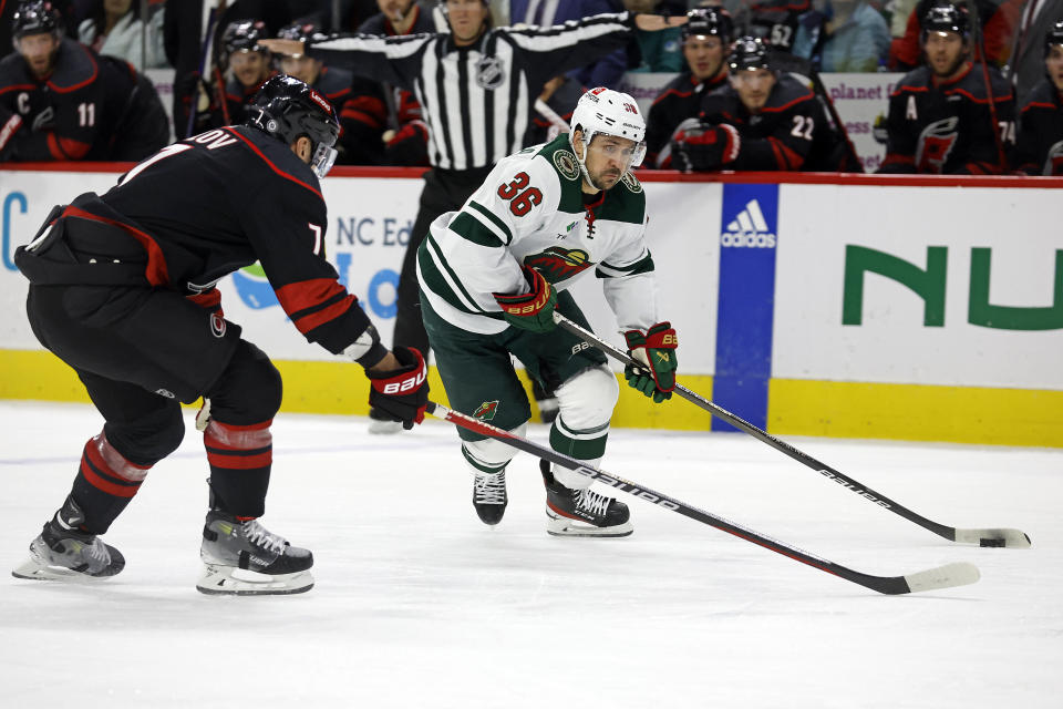 Minnesota Wild's Mats Zuccarello (36) moves the puck with Carolina Hurricanes' Dmitry Orlov (7) closing in during the first period of an NHL hockey game in Raleigh, N.C., Sunday, Jan. 21, 2024. (AP Photo/Karl B DeBlaker)