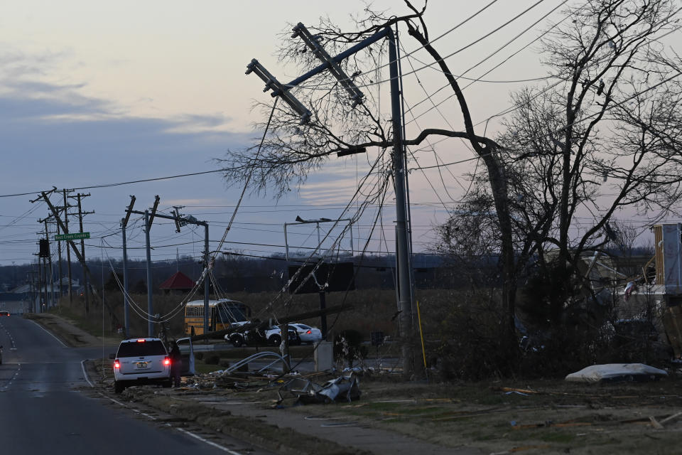 A vehicle sits by the side of the road near damaged power lines on Sunday, Dec. 10, 2023, Clarksville, Tenn. Central Tennessee residents and emergency workers are continuing the cleanup from severe weekend storms. (AP Photo/Mark Zaleski)