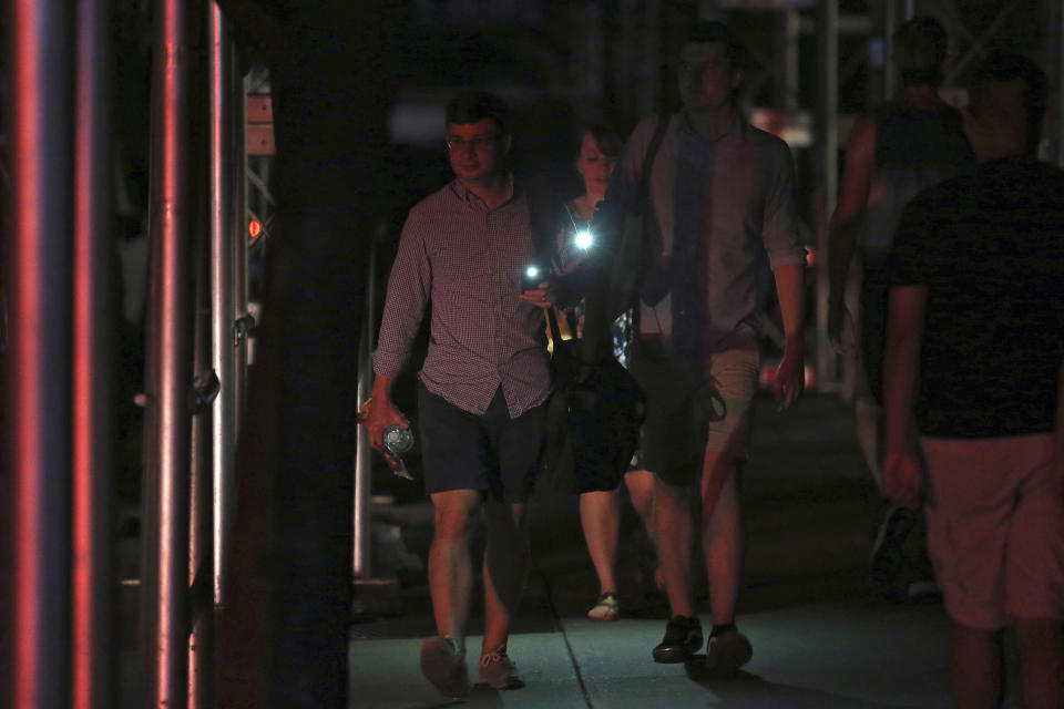 Commuters use their phones as flashlights during a widespread power outage, Saturday, July 13, 2019, in New York. Authorities were scrambling to restore electricity to Manhattan following a power outage that knocked out Times Square's towering electronic screens, darkened marquees in the theater district and left businesses without electricity, elevators stuck and subway cars stalled. (AP Photo/Michael Owens)
