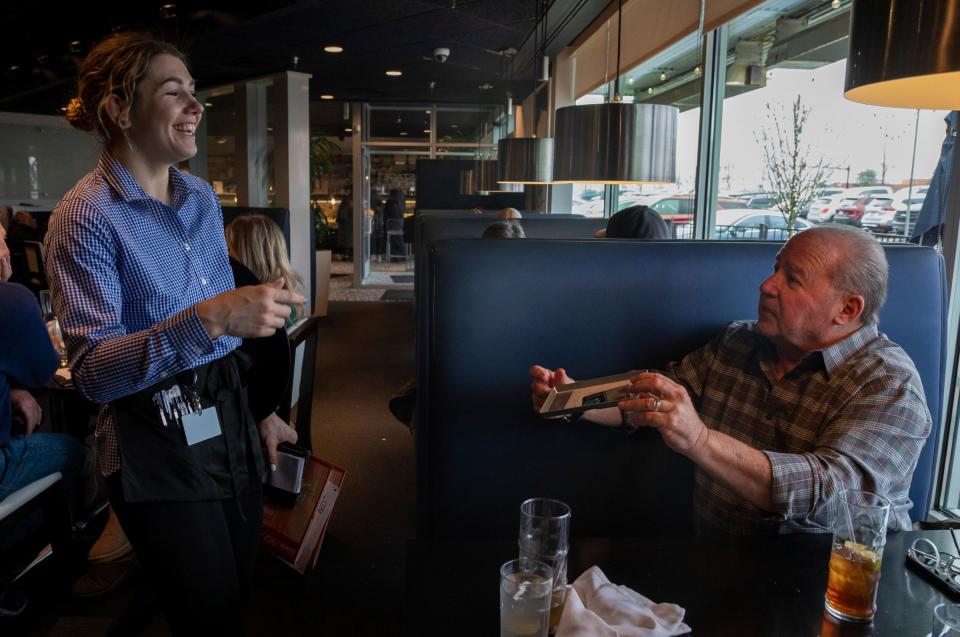 Larysa Skoblyuk grabs the check from a long-time customer of the Stage Deli Restaurant Larry Miller in West Bloomfield Township on Dec. 22, 2022.