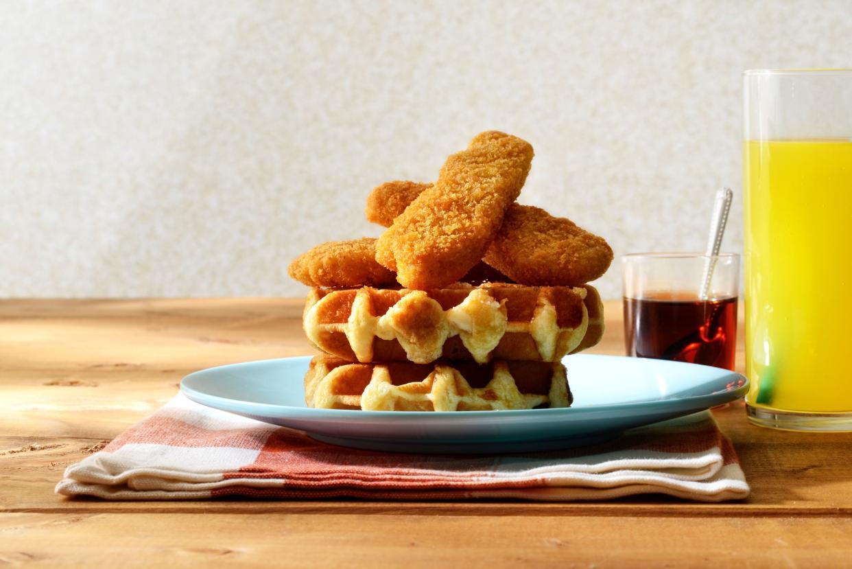 closeup of chicken tenders strips with belgian waffles on a plate with napkin