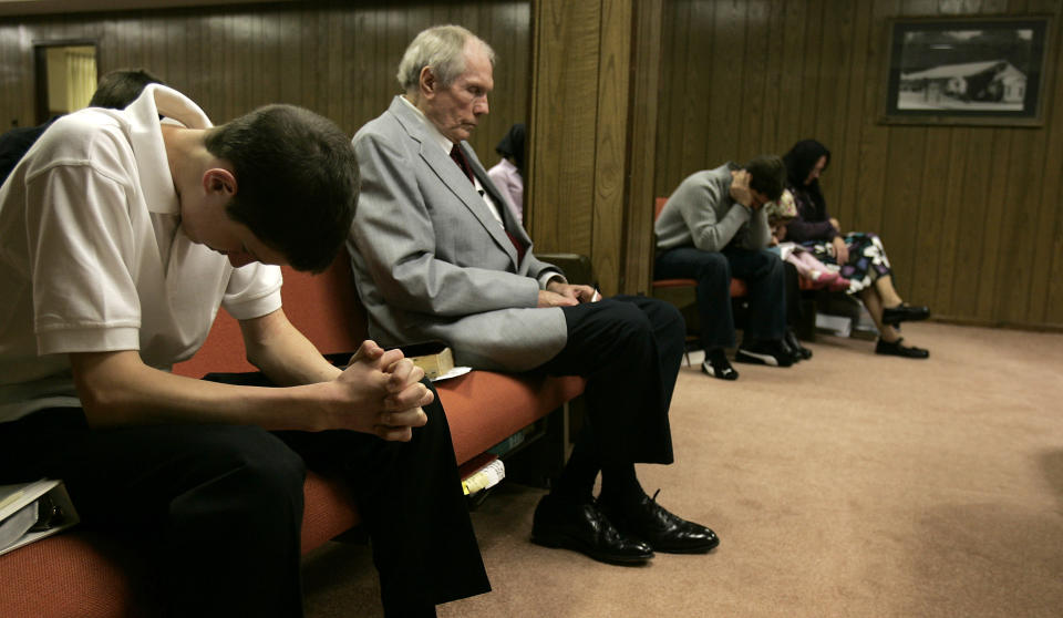 FILE - In this March 19, 2006 file photo, the Rev. Fred Phelps Sr., center, sits in prayer at his Westboro Baptist Church in Topeka, Kan. Phelps, the founder of the Kansas church known for anti-gay protests and pickets at military funerals, died Thursday, March 20, 2014. He was 84. (AP Photo/Charlie Riedel, File)