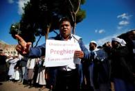 A Muslim holds a placard reading "To close a place of prayer is an act against the faith" as he attends Friday prayers in front of the Colosseum in Rome, Italy October 21, 2016, to protest against the closure of unlicensed mosques. REUTERS/Tony Gentile