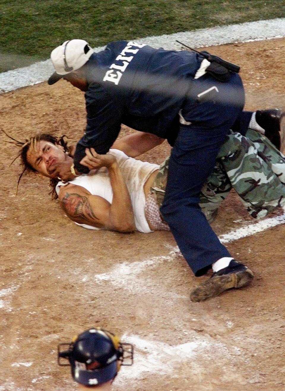 A fan who ran out on the field near home plate is caught and wrestled to the ground by a security quard during the second inning of game three of the World Series between the New York Yankees and the San Diego Padres 20 October in San Diego, Ca. The Yankees lead the best-of-seven series 2-0. (Photo by Don Emmert/AFP/Getty Images)