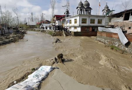 People watch as water flows from a broken embankment of a stream after incessant rains in Srinagar March 30, 2015. REUTERS/Danish Ismail