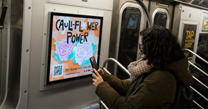 A rider on the subway in NYC snaps the QR code on one of Veganuary’s campaign ads.