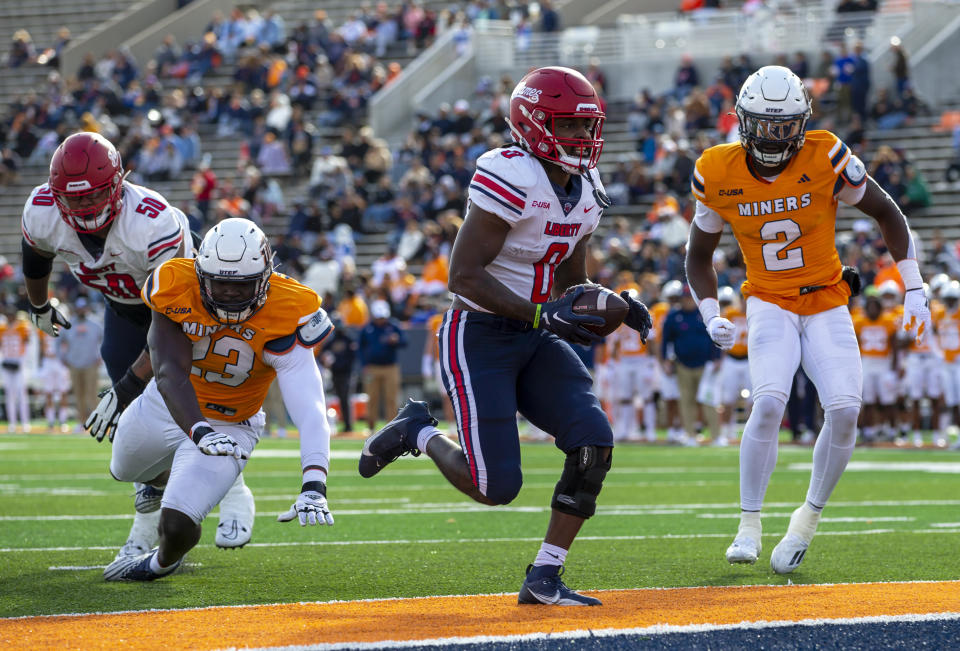 Liberty running back Billy Lucas (0) scores a touchdown past UTEP safety Kobe Hylton (2) and defensive end Praise Amaewhule (23) during the first half of an NCAA college football game on Saturday, Nov. 25, 2023, in El Paso, Texas. (AP Photo/Andres Leighton)