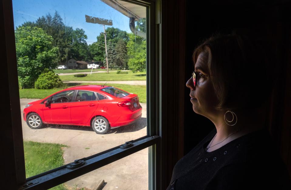 Michelle Hughes looks out the window towards her 2012 Ford Fiesta parked at her home in Flint on Wednesday, June 26, 2019. 