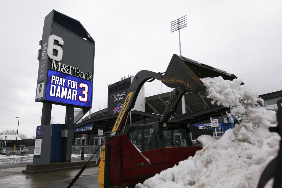 Crews clear snow from a parking lot near a sign showing support for Buffalo Bills safety Damar Hamlin outside Highmark Stadium on Wednesday, Jan. 4, 2023, in Orchard Park, N.Y. (AP Photo/Joshua Bessex)