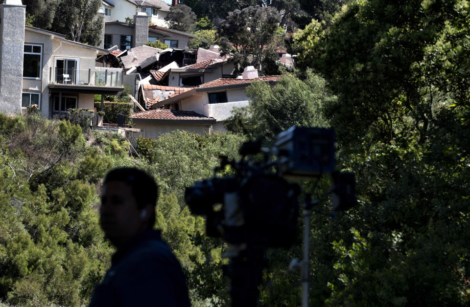 A television news cameraman gets ready for a live broadcast across a ravine from severely damaged homes in Rolling Hills Estates on the Palos Verdes Peninsula in Los Angeles County, on Monday, July 10, 2023. The homes were hastily evacuated by firefighters Saturday when cracks began appearing in structures and the ground. (AP Photo/Richard Vogel)