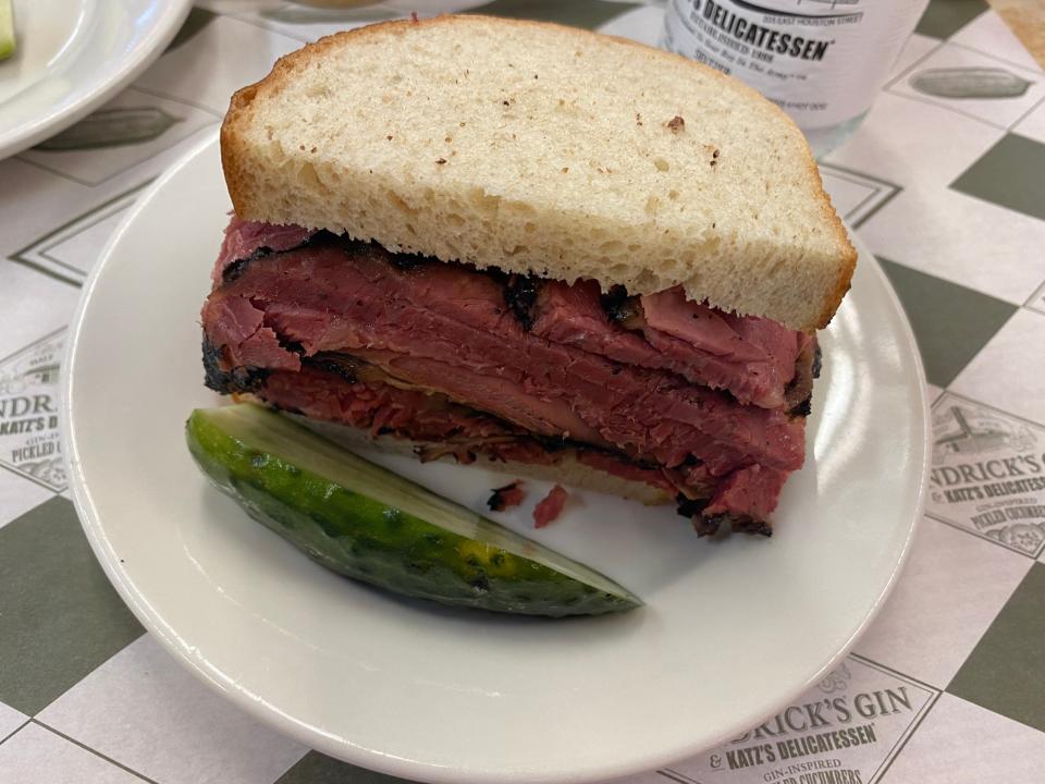 A sandwich and pickle slice on a small plate.