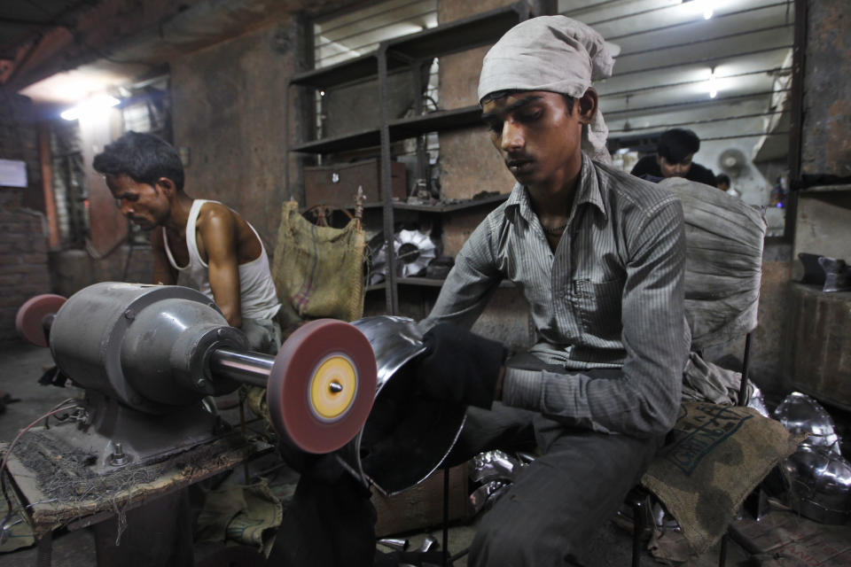 In this, June 2, 2012 photograph, laborers polish helmets being prepared for a Hollywood period movie at a workshop owned by Indian businessman Ashok Rai, unseen, in Sahibabad, India. From Hollywood war movies to Japanese Samurai films to battle re-enactments across Europe, Rai is one of the world's go-to men for historic weapons and battle attire. (AP Photo/Saurabh Das)