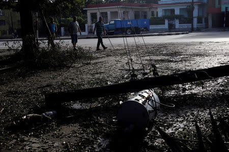 People walk near a fallen electricity pole after Hurricane Irma caused flooding and a blackout, in Havana, Cuba September 11, 2017. REUTERS/Stringer