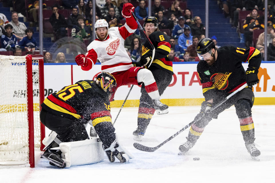 Vancouver Canucks' Filip Hronek (17) collects the puck after goaltender Thatcher Demko (35) makes a save and Detroit Red Wings' J.T. Compher (37) watches during the second period of an NHL hockey game Thursday, Feb. 15, 2024, in Vancouver, British Columbia. (Ethan Cairns/The Canadian Press via AP)