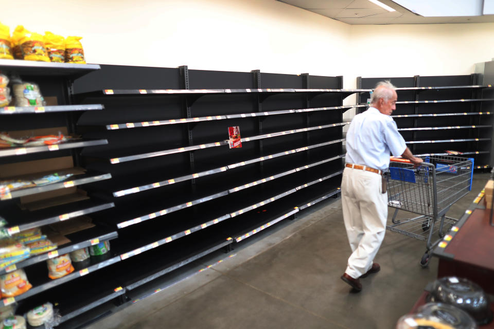 A shopper with a trolley walks past the empty bread shelves in a supermarket as people stock up before bad weather. (Photo by Joe Raedle/Getty Images)