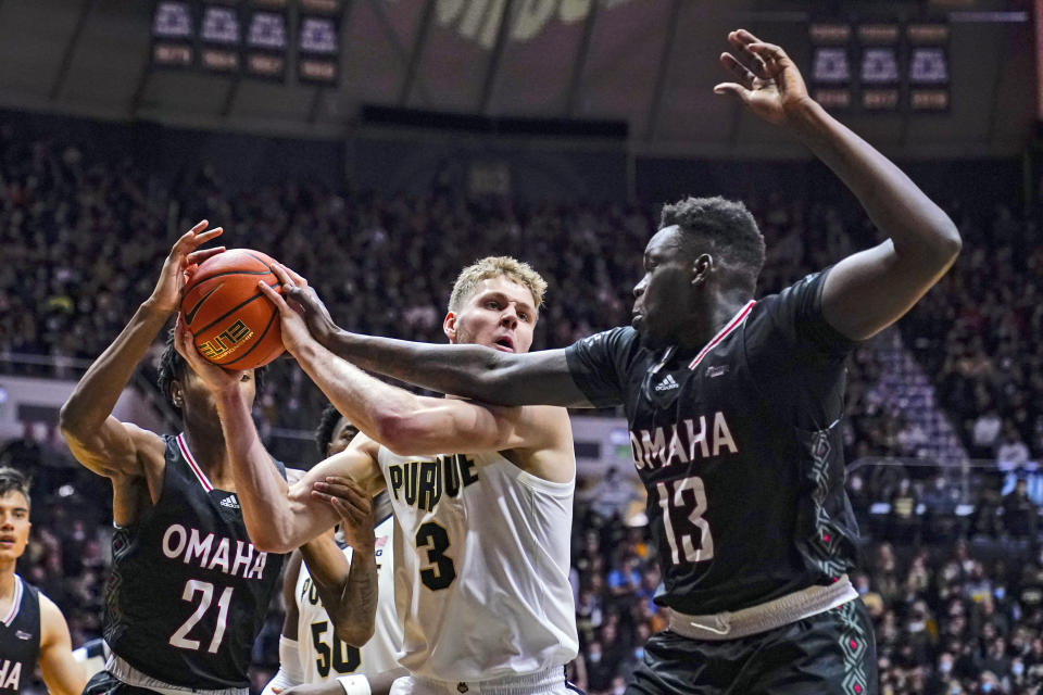Purdue's Caleb Furst (3) grabs a rebound between Omaha's Devin Evans (21) and Wanjang Tut (13) during the second half of an NCAA college basketball game in West Lafayette, Ind., Friday, Nov. 26, 2021. Purdue defeated Omaha 97-40. (AP Photo/Michael Conroy)
