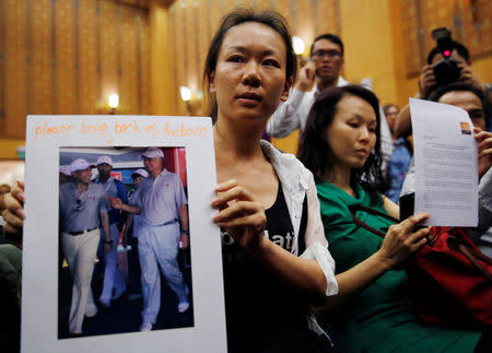 FILE PHOTO: Kelly (last name not given), 29, the wife of a passenger aboard the missing Malaysia Airlines Flight MH370, holds a picture of her husband walking with Malaysia's Prime Minister Najib Razak, at a news conference in Putrajaya January 29, 2015. REUTERS/Olivia Harris/File Photo