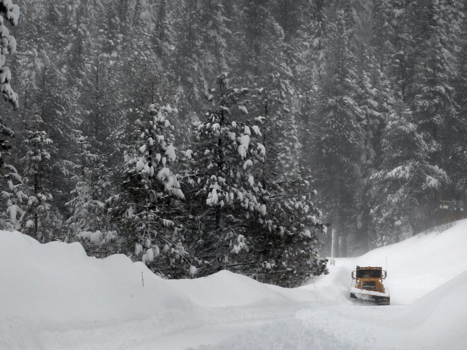 A snowplow drives among snowy evergreen trees near Lake Tahoe