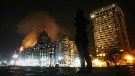 A reporter talks on her phone as smoke is seen coming from Taj Hotel in Mumbai November 27, 2008. REUTERS/Arko Datta