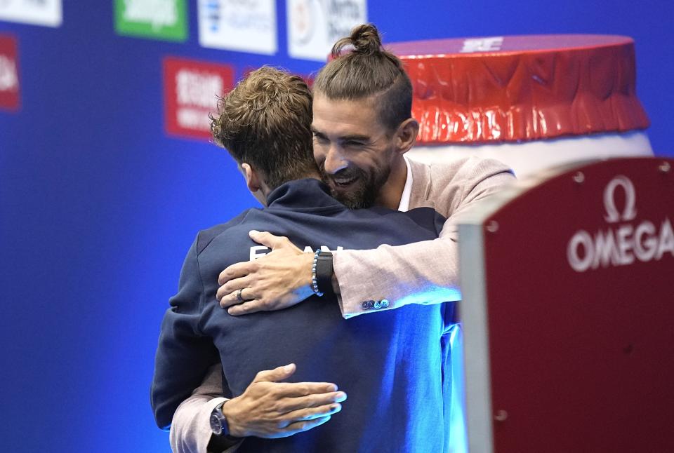 Leon Marchand, left, of France, is hugged by Michael Phelps during a medal ceremony at the World Swimming Championships in Fukuoka, Japan, Sunday, July 23, 2023. Marchand won gold setting a new world record, breaking Michael Phelps 2008 record. (AP Photo/David J. Phillip)