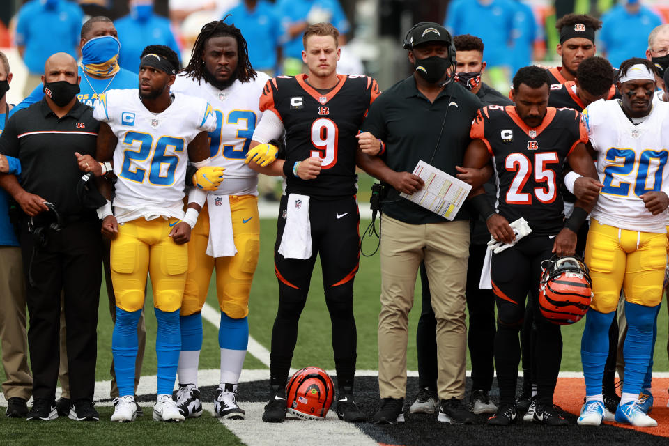 CINCINNATI, OHIO - SEPTEMBER 13: Quarterback Joe Burrow #9 of the Cincinnati Bengals, teammates and the Los Angeles Chargers stand in unity during the U.S. National Anthem at Paul Brown Stadium on September 13, 2020 in Cincinnati, Ohio. The NFL began their 2020 season and the Bengals didn't allow fans in attendance due to the Covid-19 pandemic. (Photo by Bobby Ellis/Getty Images)