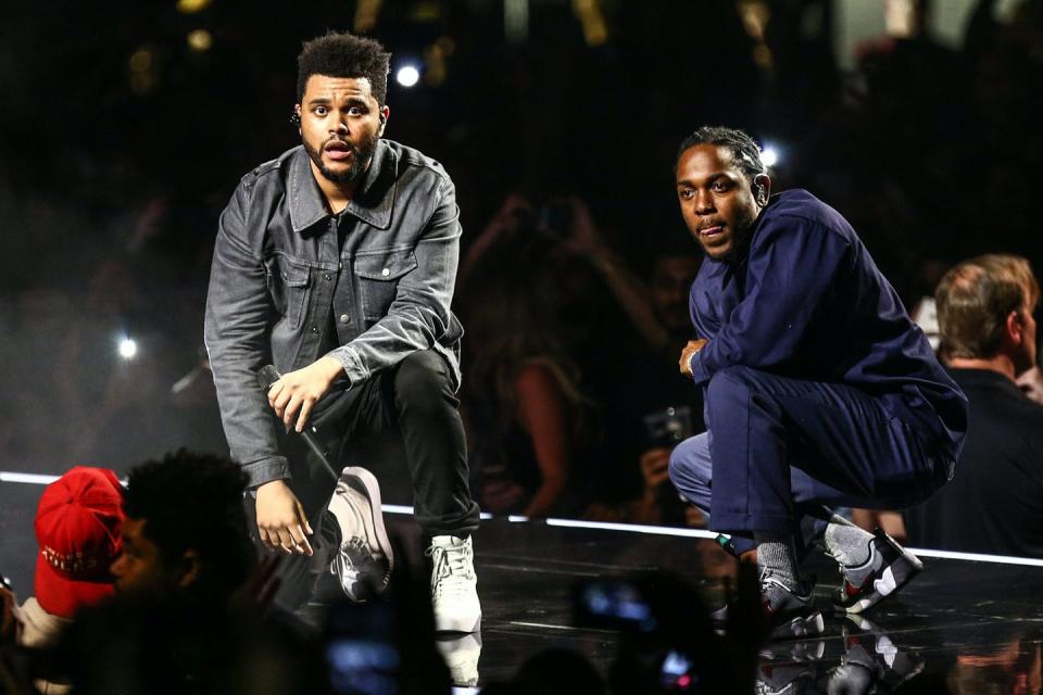 Two rappers kneel on stage.