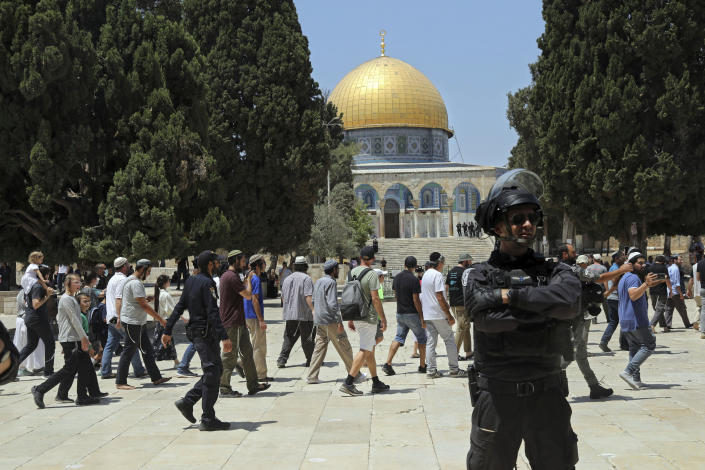 FILE - In this July 18, 2021 file photo, an Israeli police officer stands guard as Jewish men visit the Dome of the Rock Mosque in the Al Aqsa Mosque compound, during the annual mourning ritual of Tisha B'Av (the ninth of Av) -- a day of fasting and a memorial day, commemorating the destruction of ancient Jerusalem temples, in the Old City of Jerusalem, Sunday, July 18, 2021. (AP Photo/Mahmoud Illean, File)
