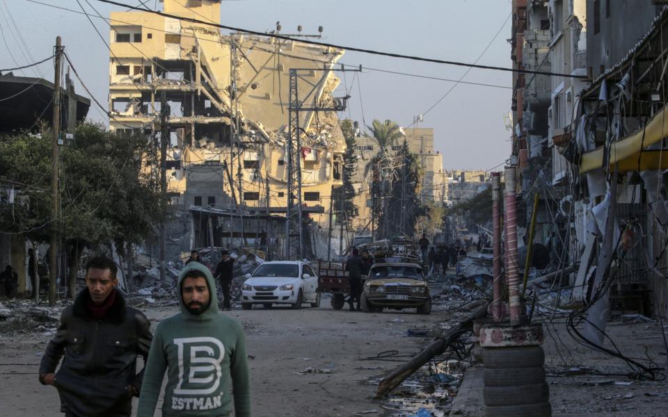 People walk among destroyed houses and buildings during Isreali military operation in Al Maghazi refugee camps in southern Gaza Strip