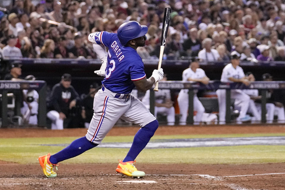 Texas Rangers' Adolis Garcia grabs his left side after his swing during the eighth inning in Game 3 of the baseball World Series against the Arizona Diamondbacks Monday, Oct. 30, 2023, in Phoenix. (AP Photo/Brynn Anderson)