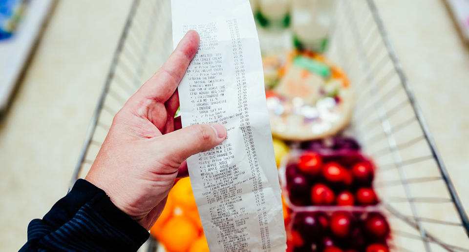 Hand holding grocery receipt in supermarket