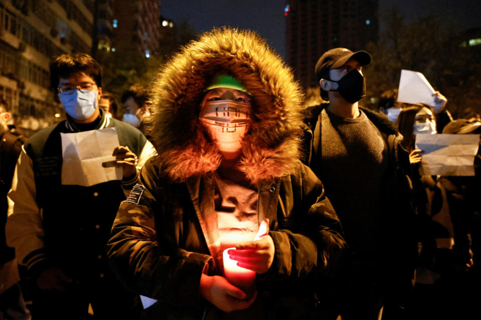 A person holds a candle as people gather for a vigil and hold white sheets of paper in protest of coronavirus disease restrictions in Beijing in November. 