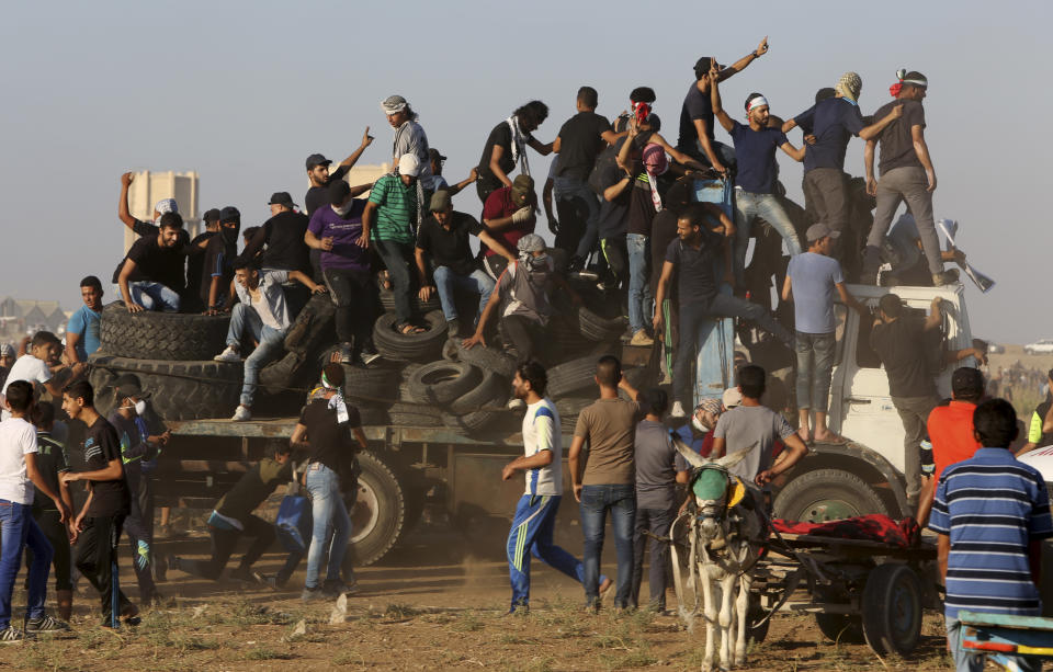 FILE-- In this Sept. 21, 2018 file photo, protesters arrive on a truck with tires to burn near the the fence of Gaza Strip border with Israel during a protest. Palestinians in the Gaza Strip have coped with shortages of just about everything in more than a decade of border closures -- from chocolate to medicines to fuel and building supplies. Now, the past six months of protests against an Israeli-Egyptian blockade have added an unexpected item to the list of those in short supply: car tires. (AP Photo/Adel Hana, File)