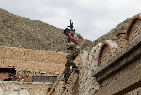 A member of Afghan Special Forces unit walks down from a roof of a house which was used by suspected Islamic State militants at the site of a MOAB, or ''mother of all bombs'', that struck the Achin district of the eastern province of Nangarhar, Afghanistan April 23, 2017. REUTERS/Parwiz