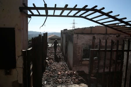 A firefighter walks at the yard of a burned house during a wildfire on Mount Hymettus, near Athens