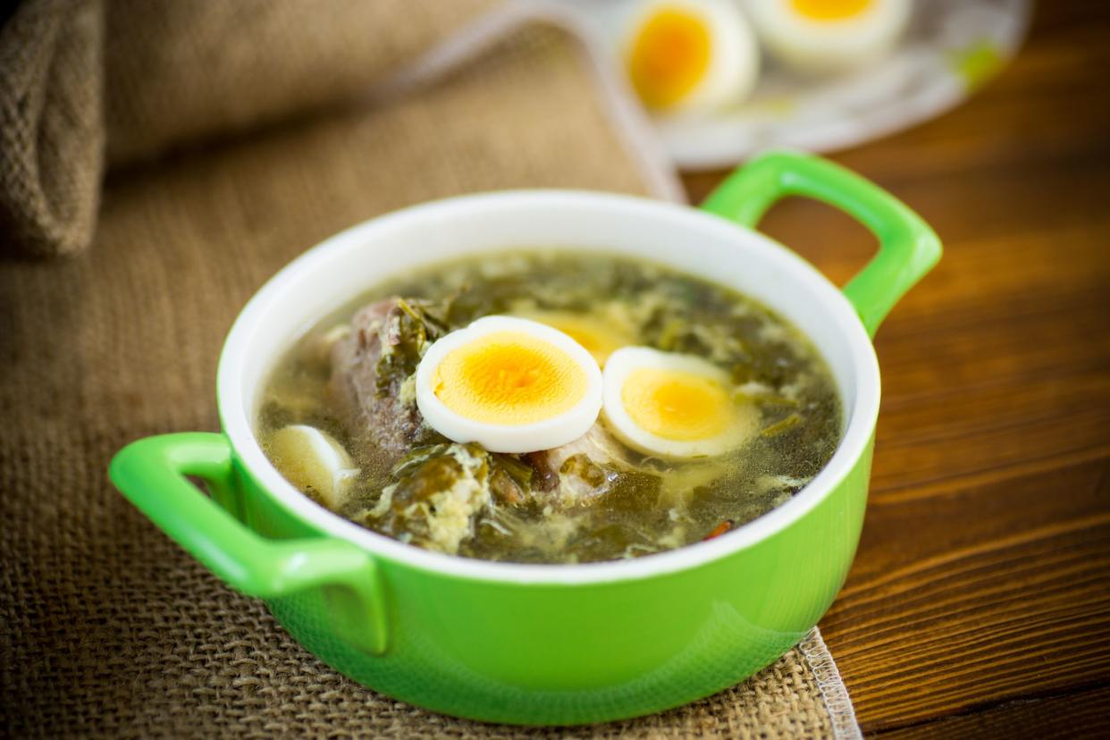 fresh spring organic soup with green sorrel and egg in a plate on a wooden table