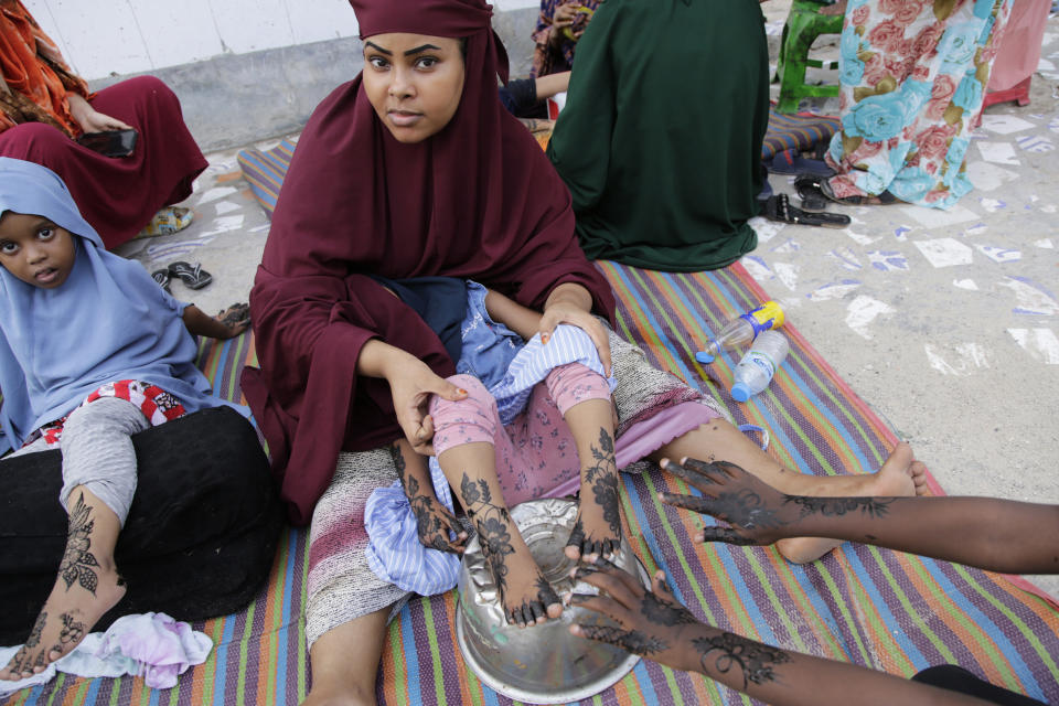 Women and children decorate their hands with henna at a street market as preparations are made for the Muslim holiday of Eid al-Fitr, next Friday, which marks the end of the holy fasting month of Ramadan, in Mogadishu, Somalia, Wednesday, April 19, 2023. (AP Photo/Farah Abdi Warsameh)