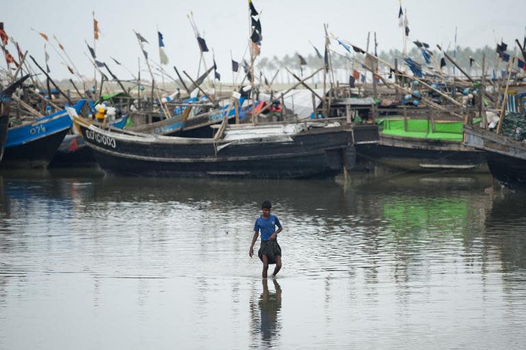 A Rohingya Muslim man walkspast fishing boats near a jetty at a refugee camp outside the city of Sittwe in Myanmar's Rakhine state on May 22, 2015