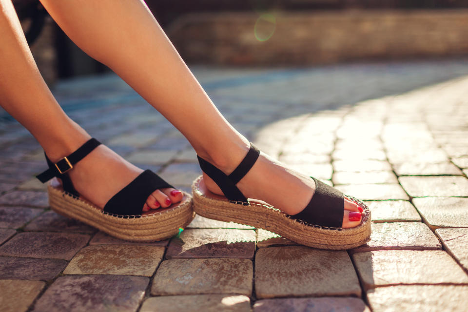 Stylish woman wearing black summer shoes with straw sole outdoors. Comfortable sandals. Beauty fashion. Footwear for Black friday sale