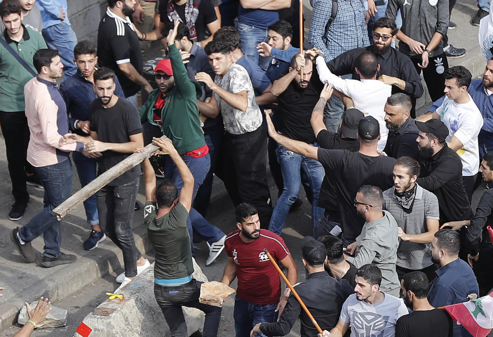 Anti-government protesters and Hezbollah supporters clash during a protest near the government palace, in downtown Beirut, Lebanon, Friday, Oct. 25, 2019. Hundreds of Lebanese protesters set up tents, blocking traffic in main thoroughfares and sleeping in public squares on Friday to enforce a civil disobedience campaign and keep up the pressure on the government to step down. (AP Photo/Hussein Malla)